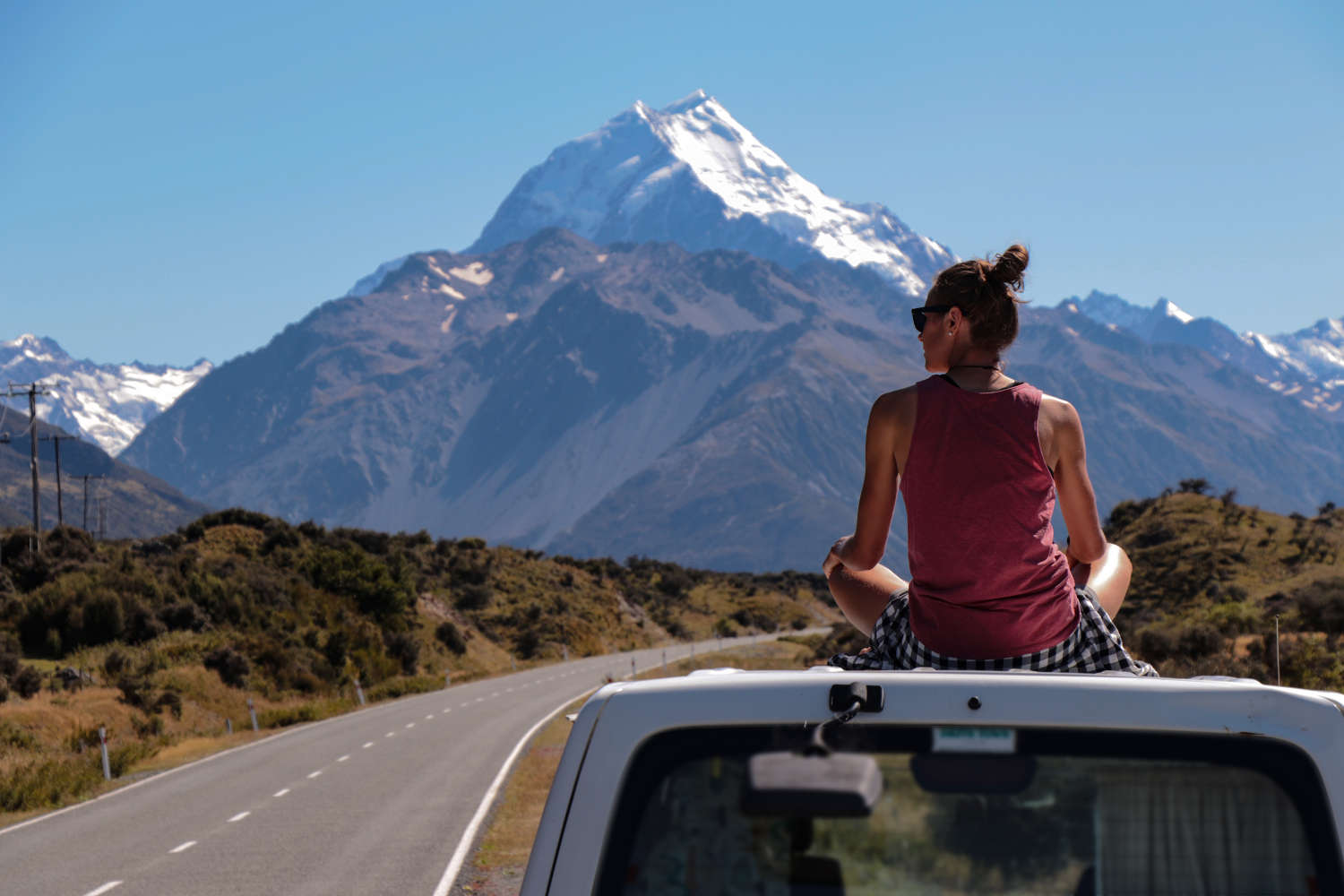 View of blurry Mount Cook with women sitting on the roof of her car, Southern Alps, New Zealand, Aoraki National park