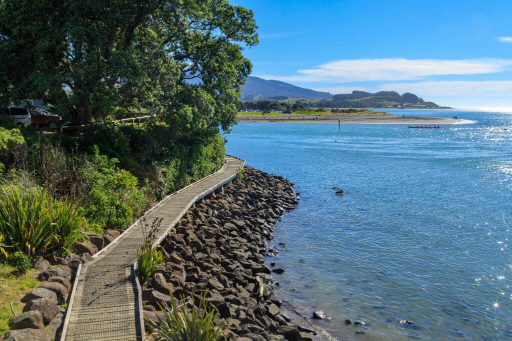 Boardwalk running along the shore, Raglan, New Zealand. In the background across the harbor is Te Kopua beach