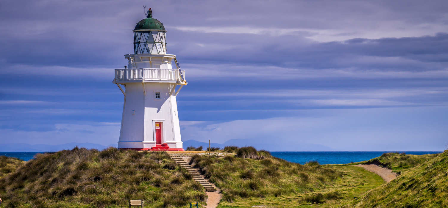 View of lighthouse on hill at Waipapa Point on New Zealand's South Island on a cloudy day