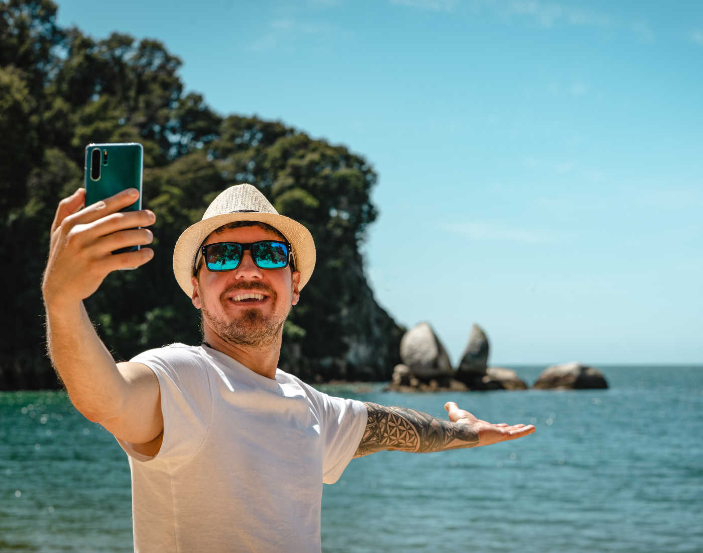Caucasian man taking a selfie with smartphone in Split Apple Rock, Abel Tasman National Park, New Zealand