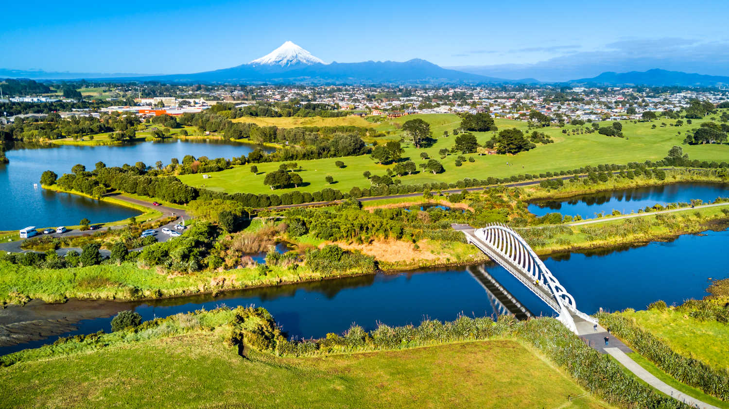 Aerial view on a beautiful Te Rewa Rewa bridge across a small stream with Mount Taranaki on the background. New Zealand